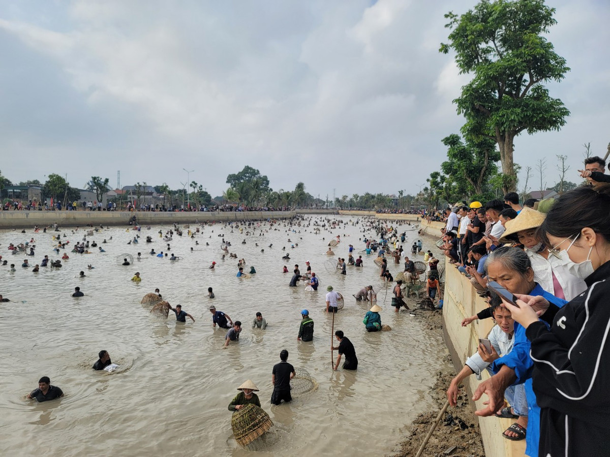 Người dân đứng trên bờ theo dõi, cổ vũ cho những người xuống nước bắt cá.