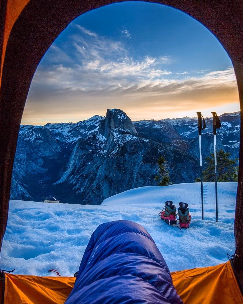 Cuộn tròn trong túi ngủ ấm áp, ngắm khung cảnh mây trời, núi và tuyết vào mùa đông tại vườn quốc gia Yosemite, Califonia, Mỹ. Ảnh: Christinhealey/Instagram.