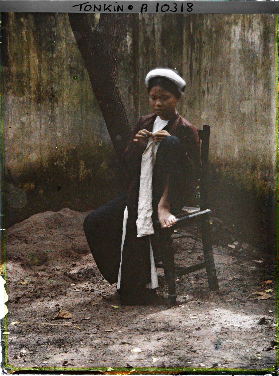 Thiếu nữ ngồi và áo, chân gác lên ghế.