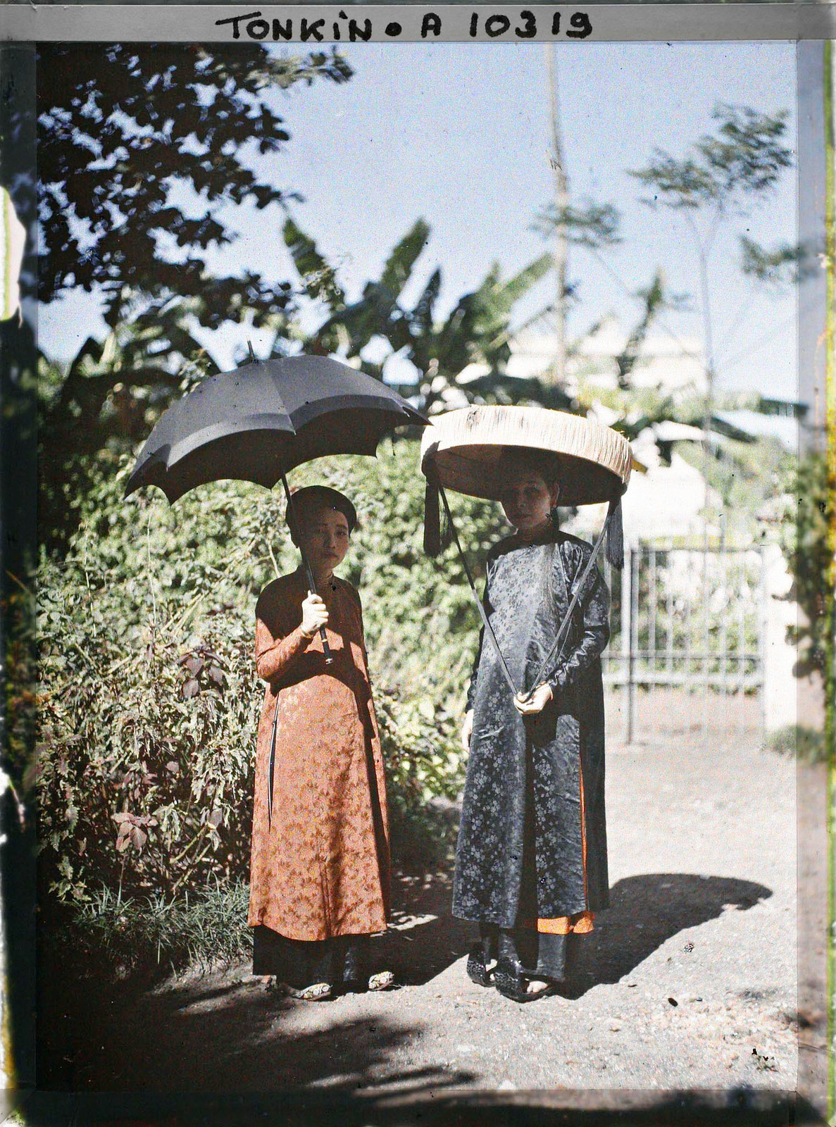 Hai quý cô, một người che ô, một người đội nón quai thao để tránh nắng.