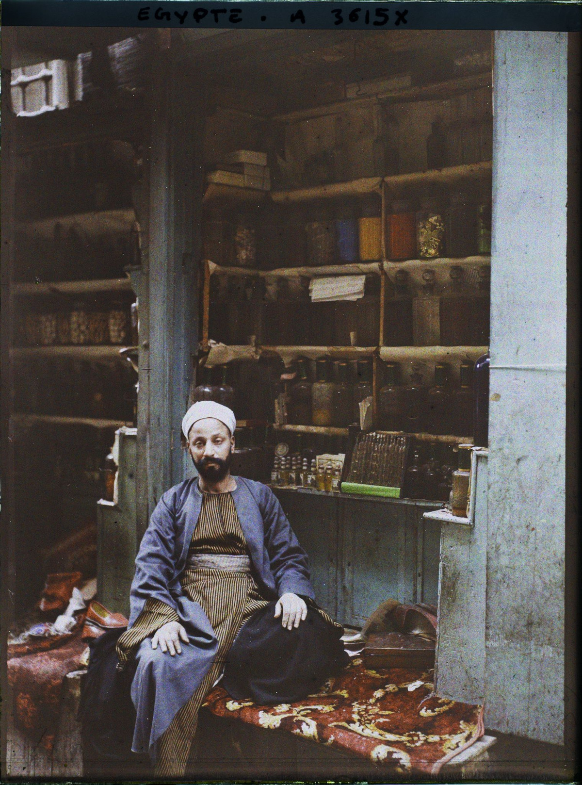 Người bán nước hoa ngồi trong cửa hàng của mình.