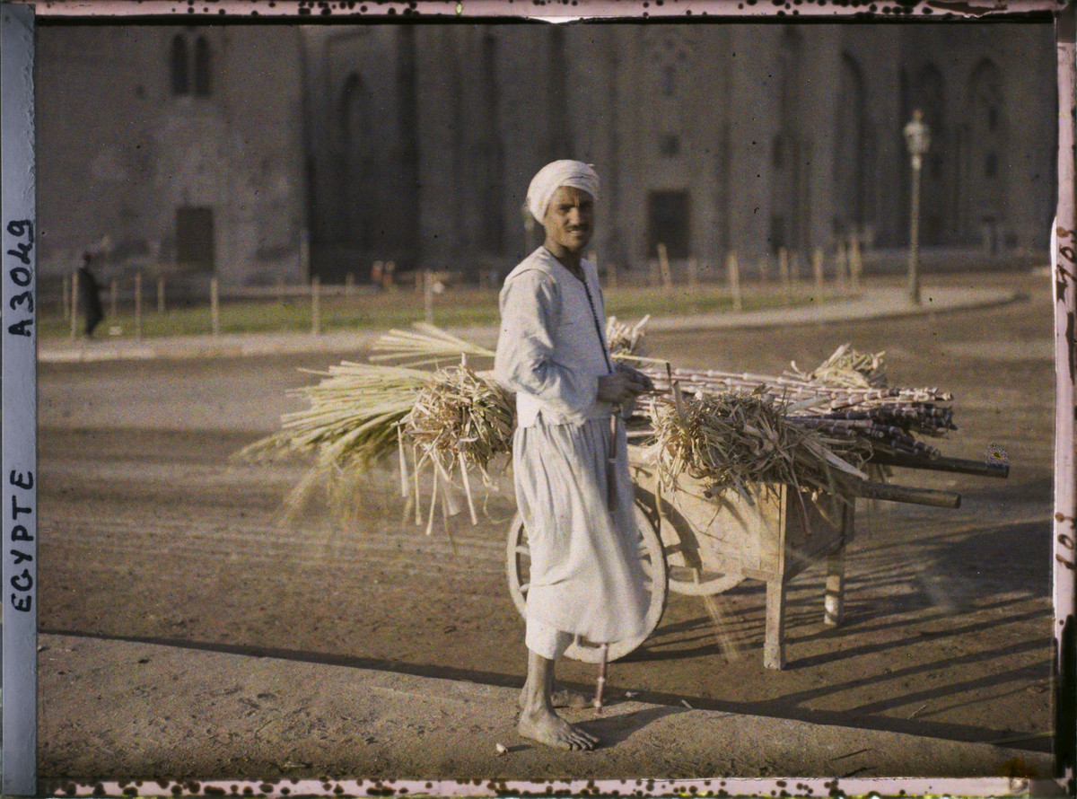 Người bán mía bên xe mía của mình.