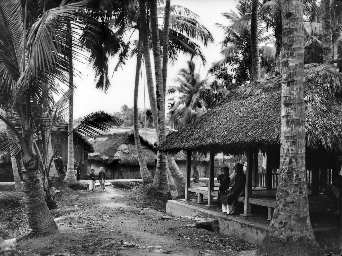 Người dân ngồi nghỉ trong ngôi nhà lợp lá.