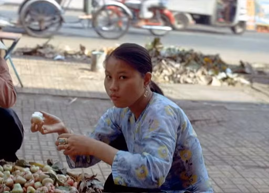 Một thiếu nữ ngồi lựa những trái mận (quả roi) trên vỉa hè.