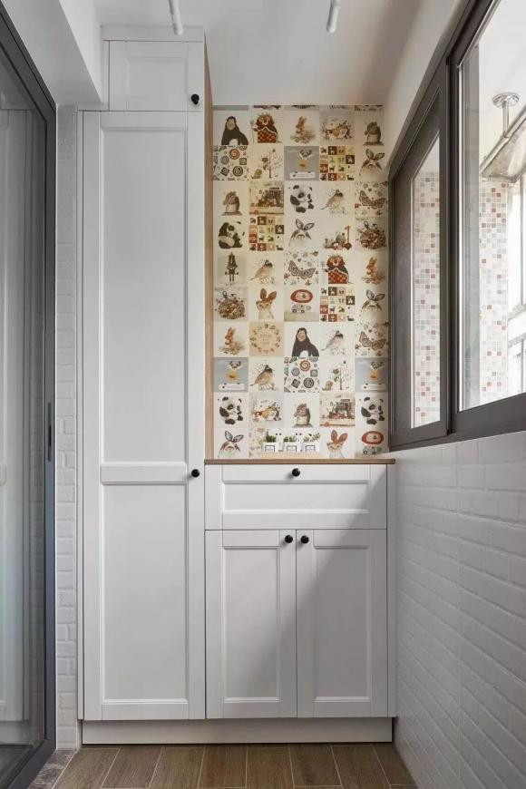 Một bên của ban công ngoài phòng khách là máy giặt và chậu rửa, bên còn lại là tủ. Một phần gạch họa tiết hoạt hình được để lại trong tủ trông nghệ thuật hơn.