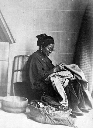 Người phụ nữ ngồi may vá quần áo.