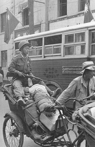 Một người lính Quốc dân đảng cầm súng ngồi trên xe chở hàng hóa.