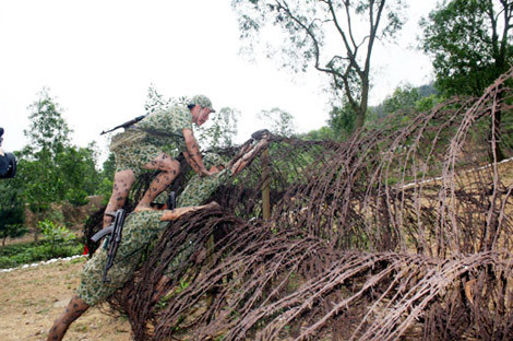 Tổ chiến đấu đặc công tự tạo thành thang để vượt qua hàng rào dây thép gai.