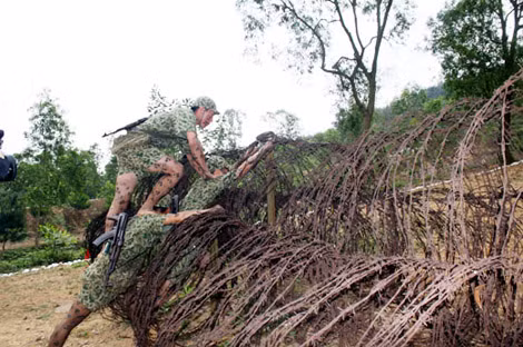 Tổ chiến đấu đặc công tự tạo thành thang để vượt qua hàng rào dây thép gai.