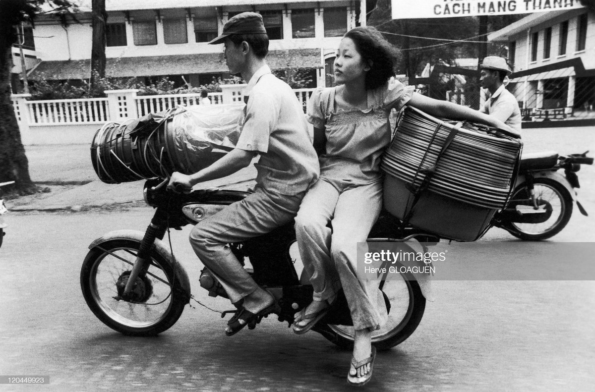 Hai vợ chồng chở hàng bằng xe máy trên đường Pasteur.