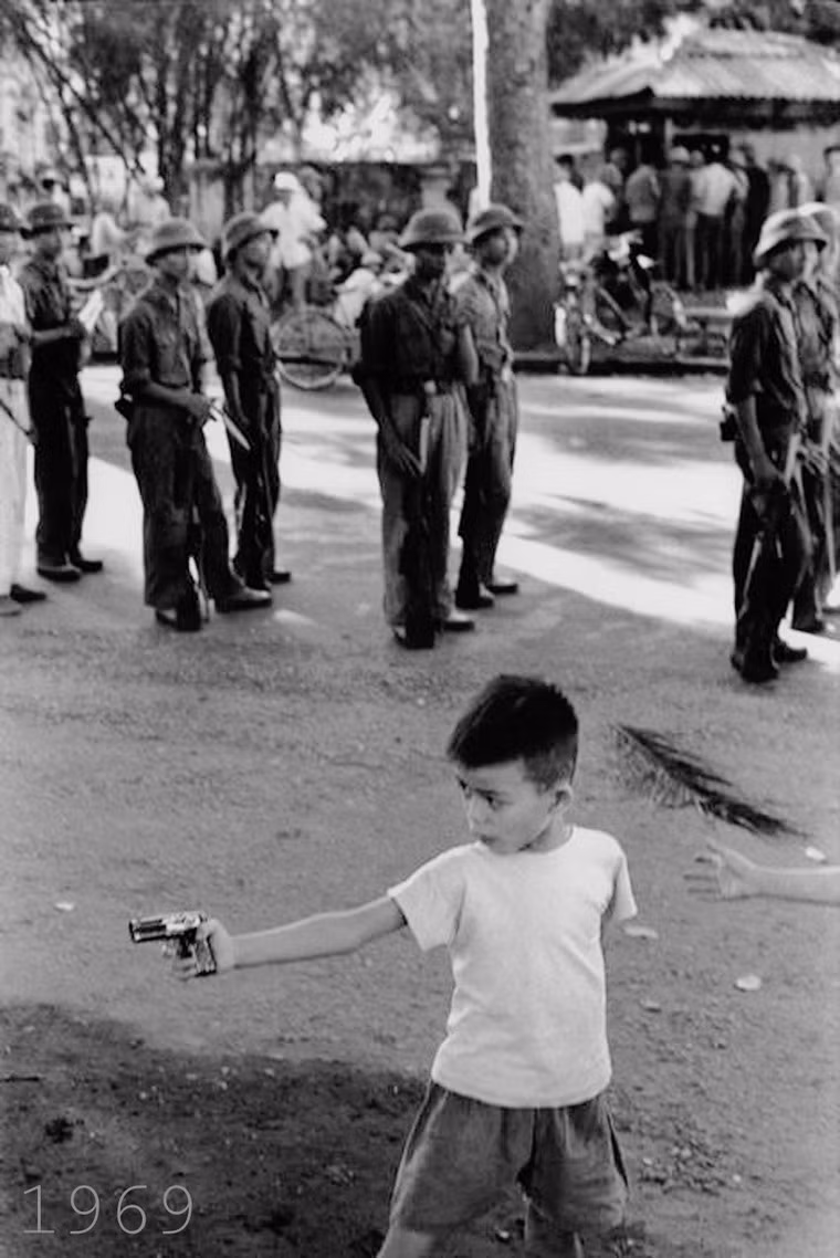 Các em bé chơi đùa với súng đồ chơi gần nơi tập kết của một đơn vị quân đội ở Hà Nội.