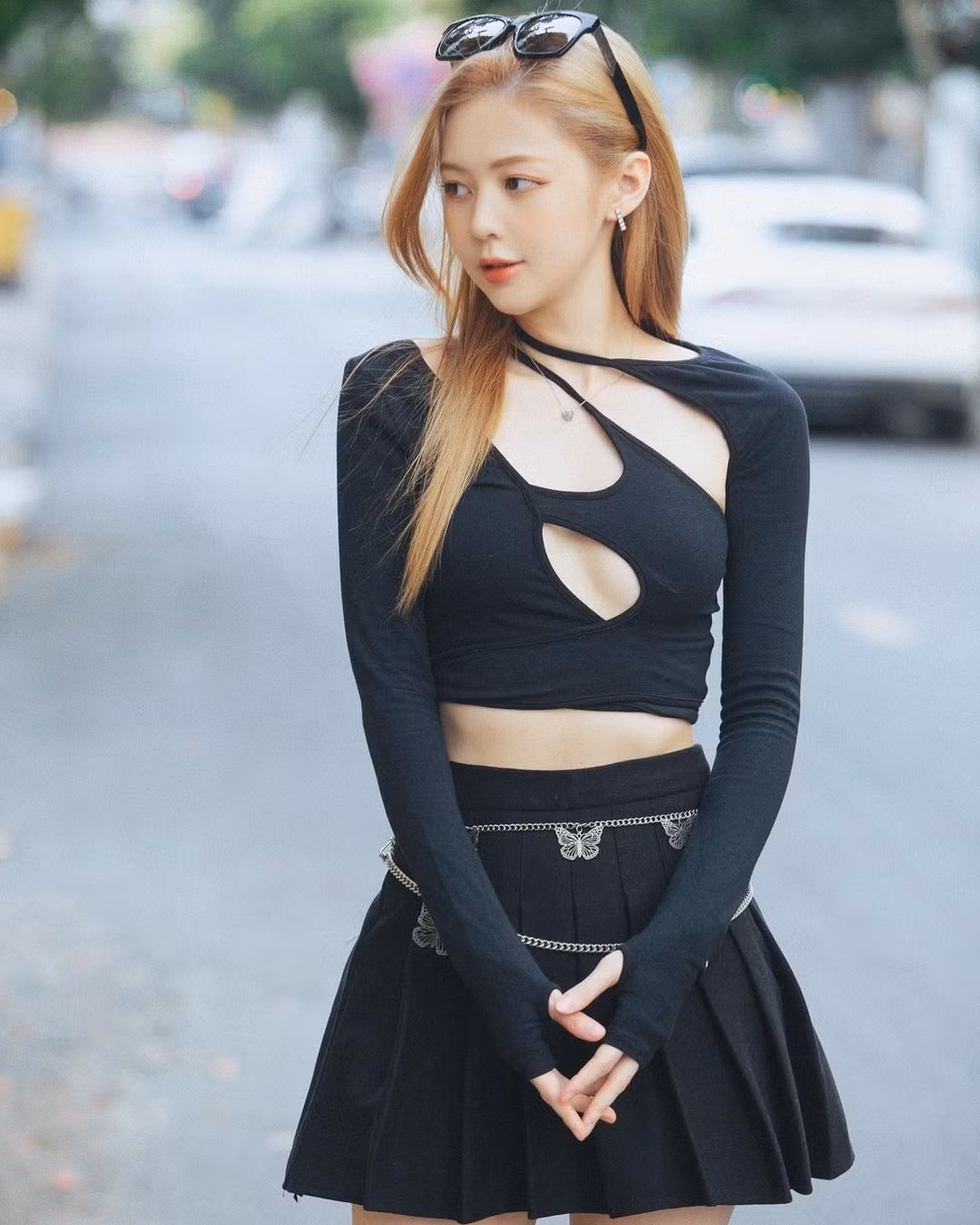 Kết hợp với áo, cô chọn mặc chân váy tennis cùng màu. Ngoài ra, cô còn đeo boots đùi bằng da và sử dụng kính mắt to bản. Tổng thể trang phục tuy không rực rỡ về màu sắc nhưng vẫn ấn tượng vì hình ảnh đa dạng nó mang đến cho người mặc. Đó là sự nữ tính vừa đủ đan xen nét năng động và cả quyến rũ.