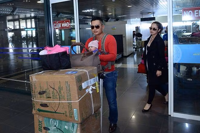 Anh vừa địu con, vừa đẩy xe hàng từ trong ga ra phía ngoài.