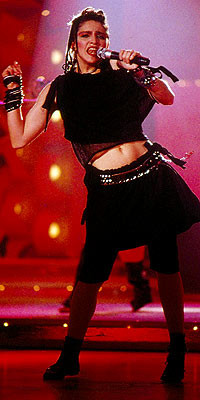 Nữ hoàng nhạc Pop trong bộ trang phục đen bằng chất liệu cao su khi trình diễn ca khúc Holiday tại Solid Gold. Bộ trang phục đã trở thành mốt thời trang được ưa chuộng nhất lúc bấy giờ.