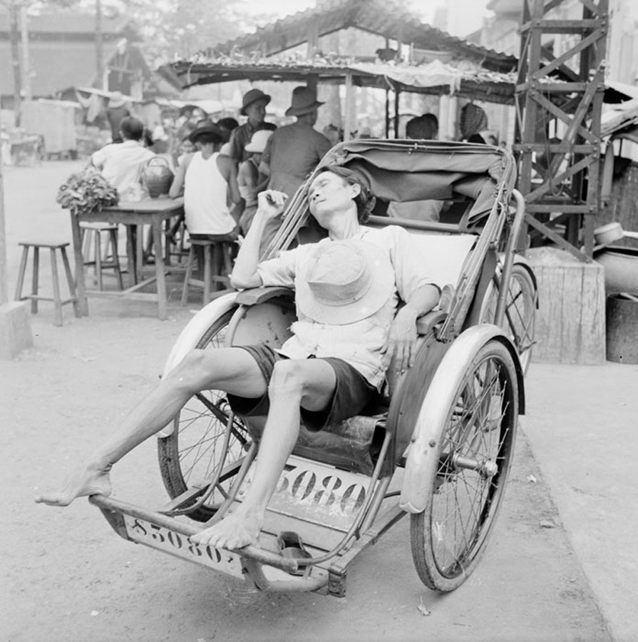 Người lái xích lô nghỉ ngơi trên chiếc xích lô của mình.