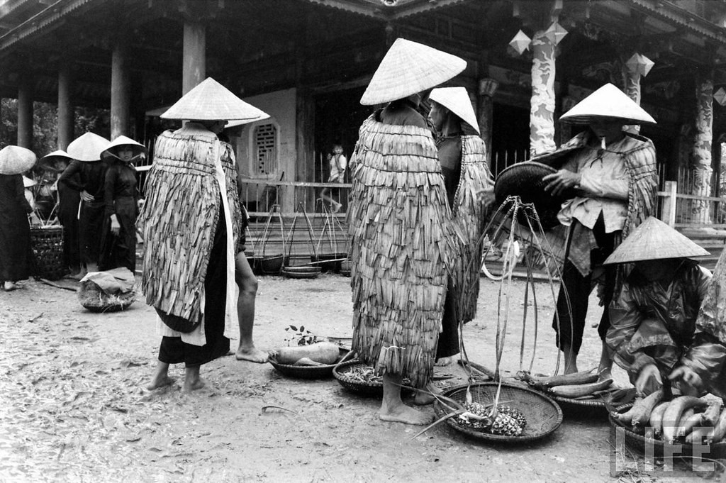 Những người nông dân mặc áo tơi tại chợ quê.