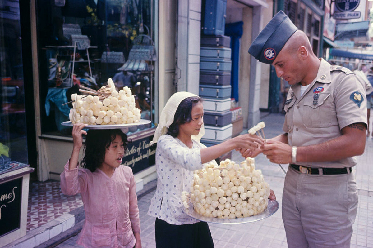Một quân nhân Mỹ mua mía ghim của một bé gái, Sài Gòn 1965. Người ăn mía ghim sẽ nhai lấy nước và nhả bã. Ảnh: Sauer Jean-Claude.