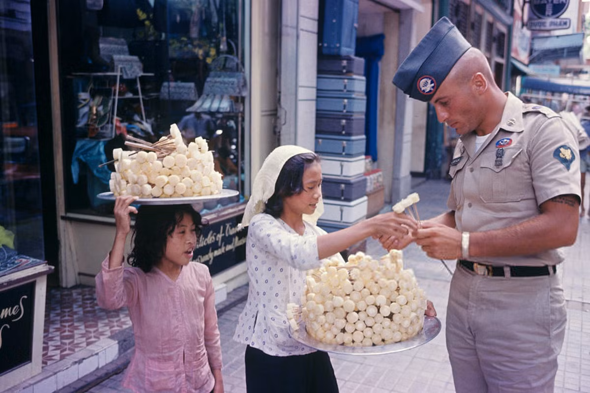 Một quân nhân Mỹ mua mía ghim của một bé gái, Sài Gòn 1965. Người ăn mía ghim sẽ nhai lấy nước và nhả bã. Ảnh: Sauer Jean-Claude.