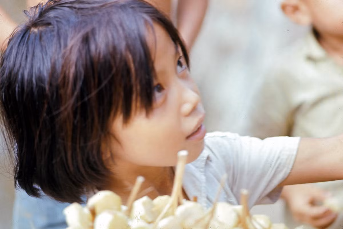 Một cô bé đưa mía ghim cho khách ở Thảo Cầm Viên thập niên 1960. Đa phần các quầy mía ghim ở Sài Gòn là do trẻ em bán.