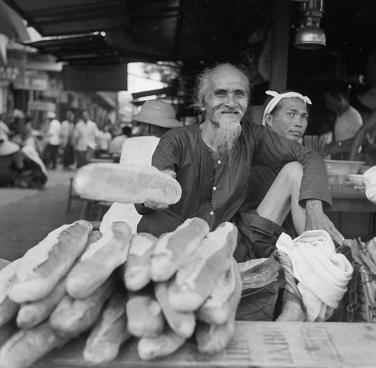 Ông lão bán bánh mì trên một con đường ở Chợ Lớn, 1956. Ảnh: Three Lions.