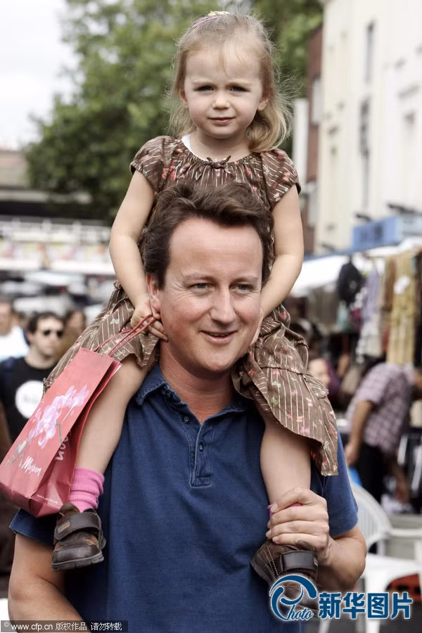 Thủ tướng Anh Cameron cõng con gái nhỏ trên vai.