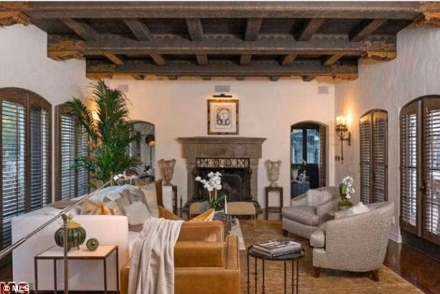 Phòng khách ấm cúng với trần nhà bằng gỗ, sàn gỗ và cánh cửa kiểu Pháp nhìn ra sân.