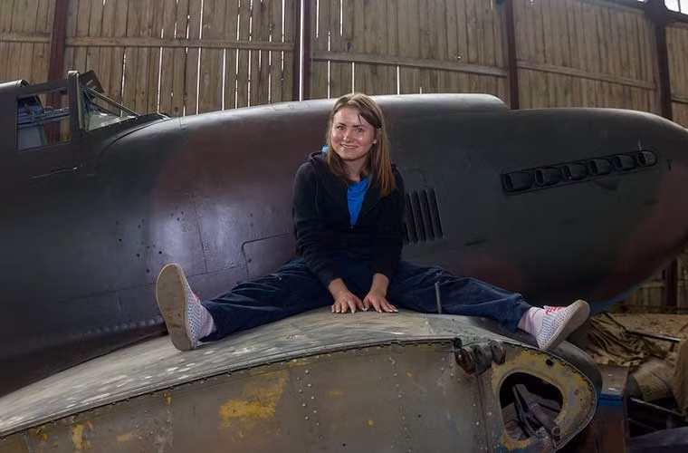 Một tình nguyện viên nữ ngồi trên cánh chiếc máy bay cường kích Il-10M được chế tạo trong Chiến tranh Thế giới thứ 2.