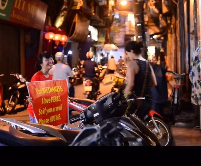 Cô bạn đi dạo trong khu phố cổ, gặp gỡ nhiều vị khách nước ngoài, cố gắng thể hiện suy nghĩ, tình cảm của mình qua tấm biển cầm trên tay...