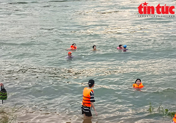 Dòng nước chảy xiết cuồn cuộn, người dân vẫn vô tư nô đùa dưới nước.