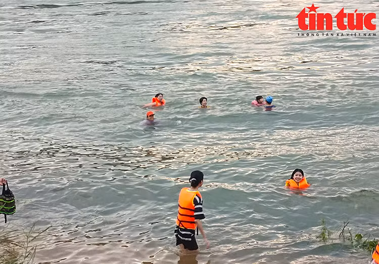Dòng nước chảy xiết cuồn cuộn, người dân vẫn vô tư nô đùa dưới nước.