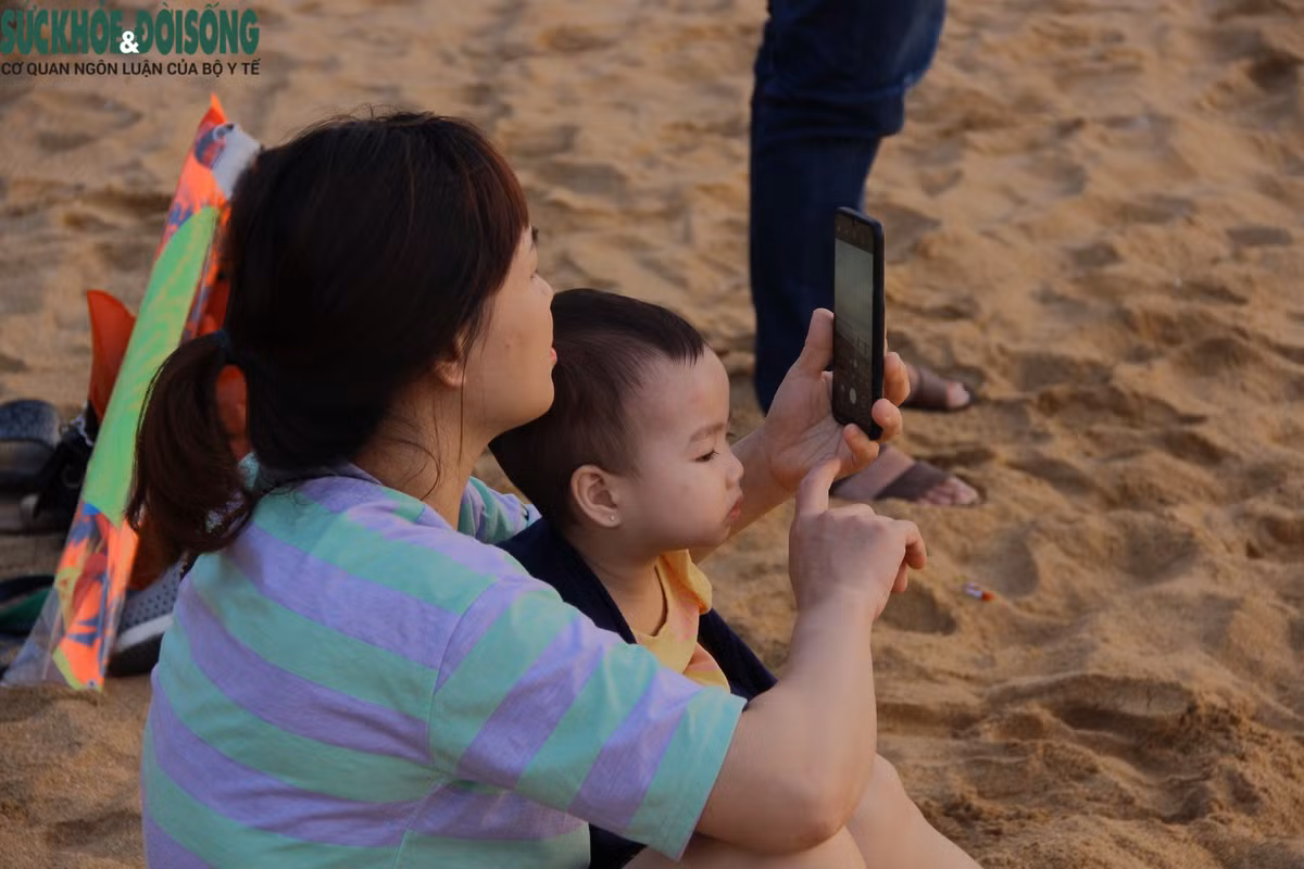 Các bậc cha mẹ dẫn con tới biển chơi dịp nghỉ lễ.