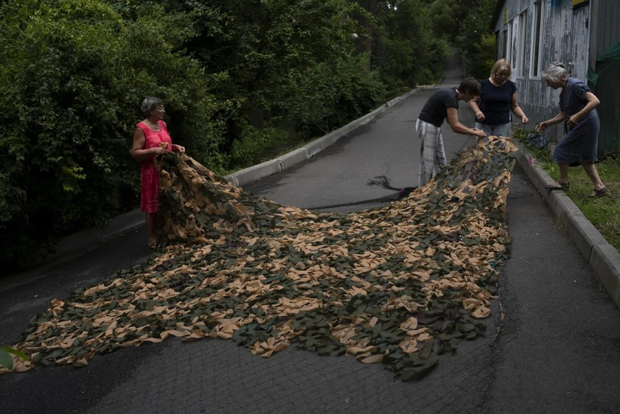 Một nhóm người dân may tấm vải ngụy trang để đưa ra tiền tuyến. Ảnh: AP. 