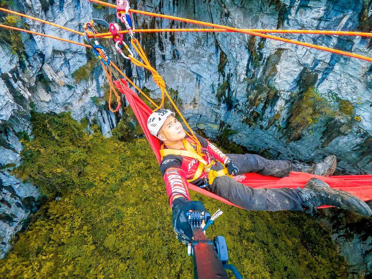 Thực vật bên dưới hố đa dạng, có nhiều cây dương xỉ khiến du khách cảm thấy như đang xuyên không, khám phá thời tiền sử. Anh Minh Quang, một du khách trải nghiệm đu dây ở hố sụt Mèo Vạc cho biết, nhóm anh căng 2 sợi zipline (một loại ròng rọc) trên miệng hố. Vừa đảm bảo an toàn, vừa đảm bảo độ căng. Dùng hết khoảng 300m dây, loại dây static vừa làm zipline, làm điểm neo và dây lên xuống. Thời gian thiết kế 4-5 tiếng. (Ảnh: Minh Quang).