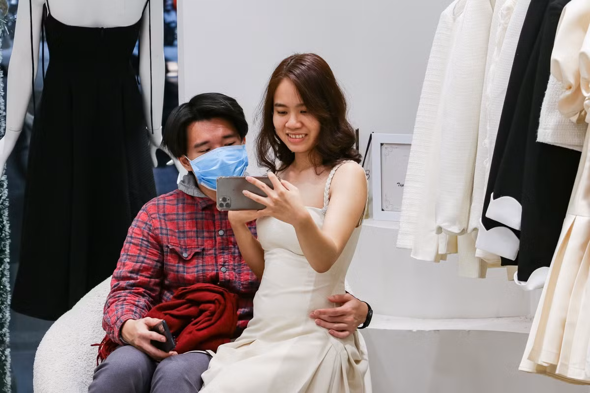 Minh Tùng (24 tuổi) đã ngồi gần 30 phút ở cửa hàng thời trang. Anh dành phần lớn thời gian lướt điện thoại, trừ những khi bạn gái tiến tới và hỏi ý kiến về bộ quần áo cô đang diện. Anh thường khen ngợi mỗi khi người yêu chọn được bộ đồ ưng ý. "Đi mua sắm quần áo với cô ấy thực ra rất vui. Phần mệt nhất là khi phải dắt xe ra vào liên tục thôi", anh nói.