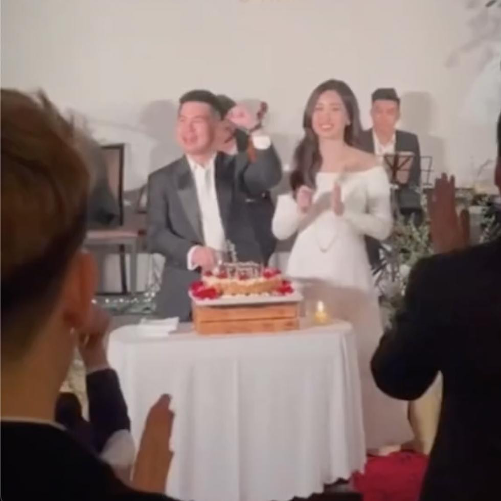 rong khi con trai út Bầu Hiển chỉn chu với vest thì Hoa hậu Việt Nam 2016 mặc váy trễ vai ôm sát để lộ vòng 2 hơi tròn.