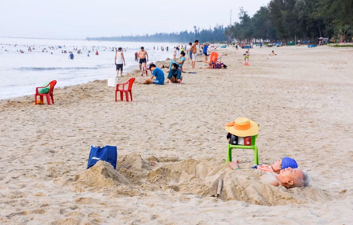 Đôi vợ chồng già vùi mình trong cát rèn luyện sức khỏe ở bãi biển Mỹ Khê, TP Quảng Ngãi.