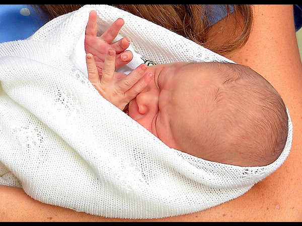 Được đưa ra ngoài ánh nắng mặt trời, bé có vẻ khá khó chịu và đưa tay lên mút.