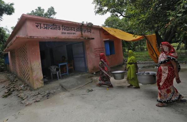 Đầu bếp mang đồ dùng nhà bếp đi rửa sau khi các em học sinh dùng xong bữa ăn.