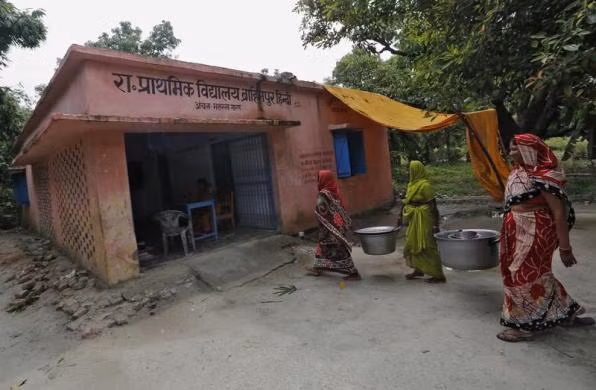 Đầu bếp mang đồ dùng nhà bếp đi rửa sau khi các em học sinh dùng xong bữa ăn.