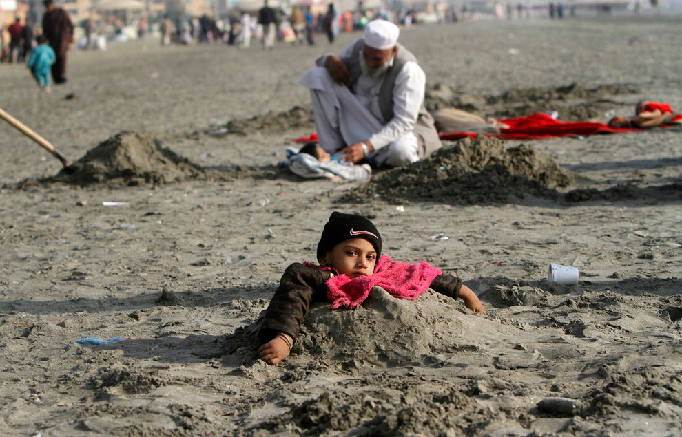 Cô bé Lubna 9 tuổi bị khuyết tật đang được chôn dưới cát ngập đến ngực trong lúc hiện tượng nhật thực xảy ra ở bãi biển Cliffton thuộc thành phố Karachi, Pakistan.