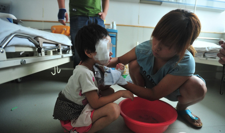 Mẹ bé đang vệ sinh mặt và cơ thể cho bé trong bệnh viện.