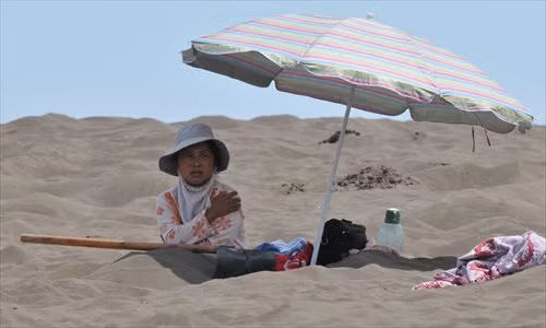 Một phụ nữ ở Turpan, khu vực tự trị Tân Cương chôn chân trong cát nóng. Họ cho rằng liệu pháp này có thể chữa một số bệnh mãn tính, bao gồm viêm khớp dạng thấp và huyết áp cao.