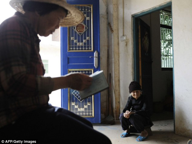 Con dâu cụ đang kiểm tra lại giấy khai sinh của cụ.