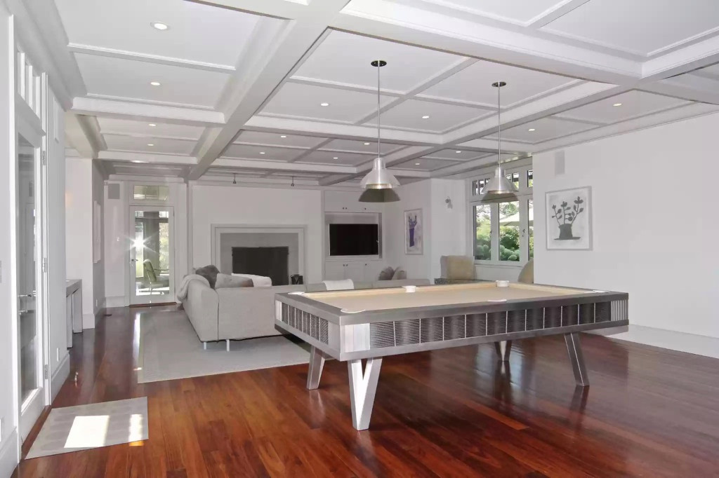 Tương đồng với cấu trúc phòng bếp, phòng giải trí lát sàn gỗ và trần thiết kế bằng gỗ sơn trắng. Chính giữa căn phòng là bàn bi-a có màu xám, tiệp với màu sơn trắng của căn phòng. Ảnh: Realtor.