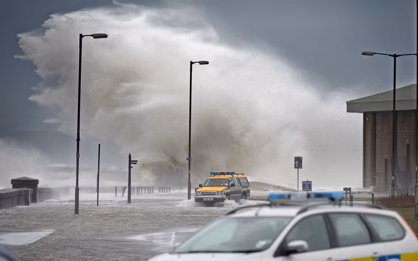 Cảnh sát và các thành viên của đội tuần tra bờ biển đi tuần ở Saltcoats, Scotland trong mưa bão, lũ lụt.