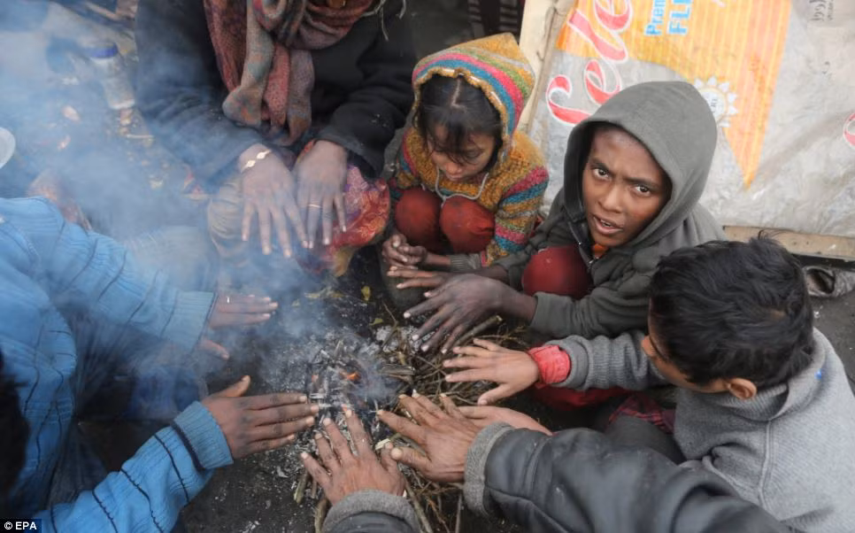 Những đứa trẻ nghèo khổ mặt mũi lấm lem, gầy guộc, quần áo ránh nát ngồi sưởi ấm quanh một nhúm cành khô đang cháy leo lắt, chống chọi với cái lạnh dưới 0 độ C tại khu ổ chuột ở Srinagar.