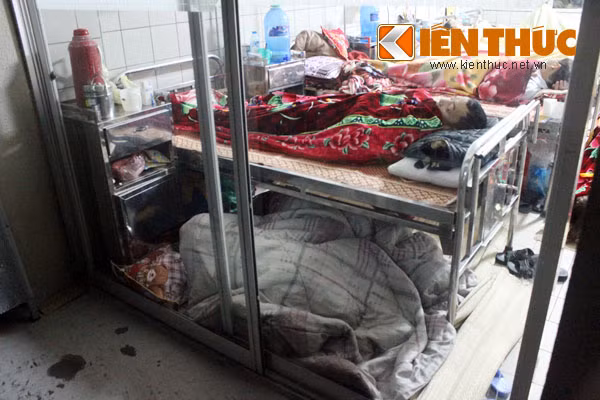 Với những bệnh nhân tỉnh xa, kinh tế eo hẹp, việc người nhà ngủ vạ vật ở bất cứ chỗ nào nằm được trong bệnh viện là một cách tiết kiệm phí thuê phòng trọ, và cũng để tiện chăm sóc, phục vụ nhau. Trong hình là cảnh người nhà nằm ngay dưới chân giường bệnh, trên sàn. Ngủ như vậy là đã "sang trọng", ấm cúng rồi..