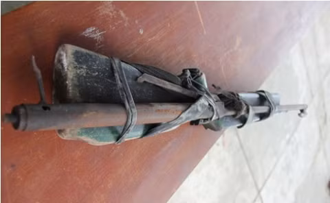 Bộ phận cò của khẩu súng tự chế có nòng là ống sắt được nẹp vào một phần của súng thật đã hư hỏng.