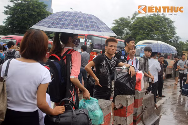 Nhiều người nóng lòng đứng dưới mưa để đợi xe.