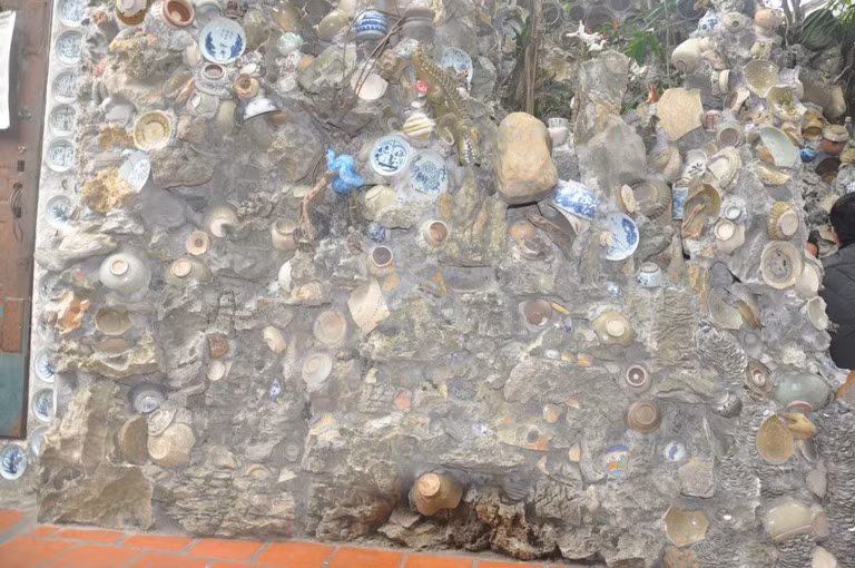 Hòn non bộ phía trước ngôi nhà cũng được gắn đồ cổ rất độc đáo.